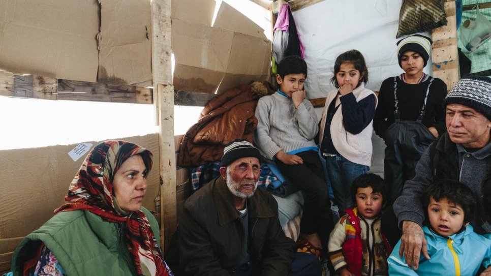 Sardar (à direita) em sua pequena cabana de madeira em Lesbos, acompanhado por seus filhos, sogra e sogro, que é cego e teve que ser carregado no caminho até a Grécia