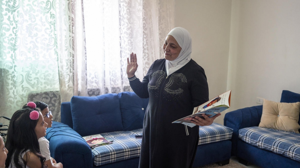 A embaixadora do We Love Reading Latifa Al-Laham, 55, lê para um grupo de jovens refugiados sírios em um apartamento em Amã, Jordânia